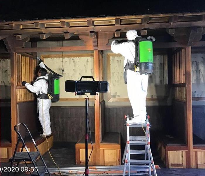 SERVPRO technicians dressed in PPE Removing Black Soot from Walls and Ceilings with Chemical Sponge