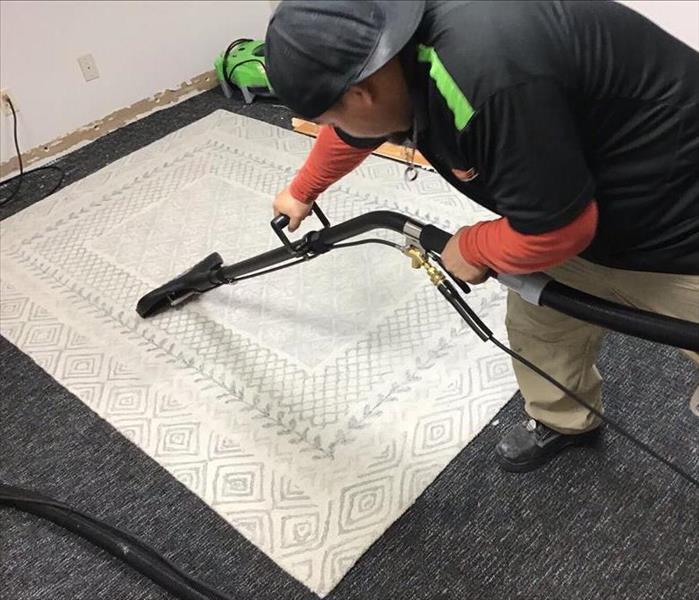 SERVPRO Technician extracting standing water from white Carpet